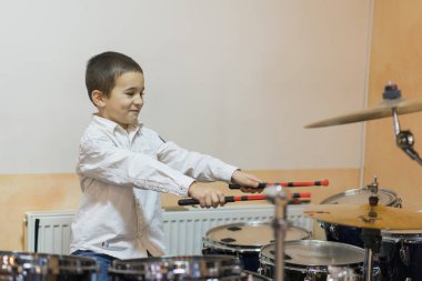 Boy drumming. Boy in white shirt playing the drums.