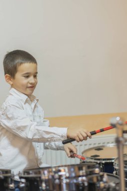Boy drumming. Boy in white shirt playing the drums.