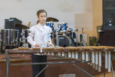 Teenager girl in white shirt boy playing the marimba.