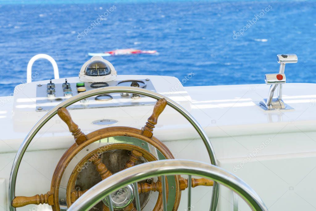 Yacht steering wheel on blue sky background.
