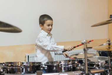 Boy drumming. Boy in white shirt playing the drums.
