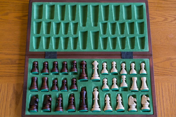 Wooden chess set in box, view from above with brown background.