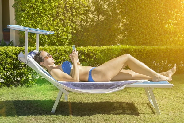 夏のライフスタイルの肖像画の若いです見事な女性がビーチで日なたぼっこをして — ストック写真