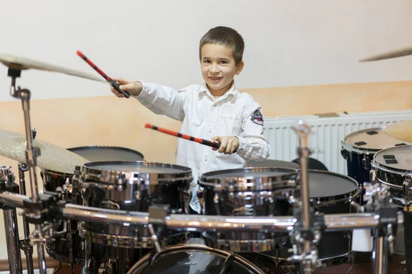 Boy drumming. Boy in white shirt playing the drums.