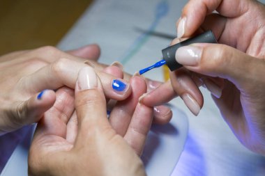 Manikür işlemi. Oje sürme, mavi jel cilası..