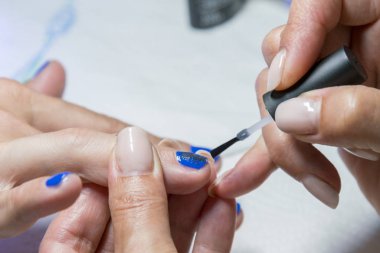 Manikür işlemi. Oje sürme, mavi jel cilası..