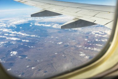 Bulutlar ve gökyüzü bir uçağın penceresinden görülüyor. Uçağın penceresi.