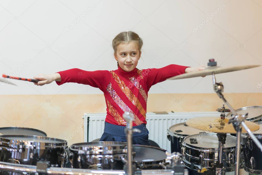 Teen girl playing the drums in music class.