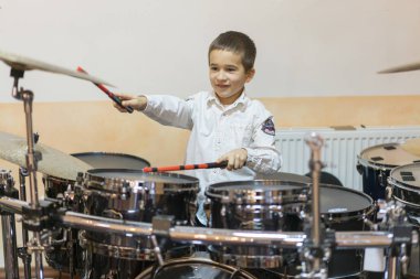 Boy drumming. Boy in white shirt playing the drums.