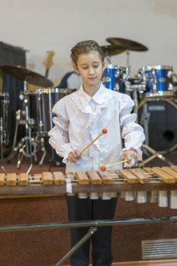 Teenager girl in white shirt boy playing the marimba.