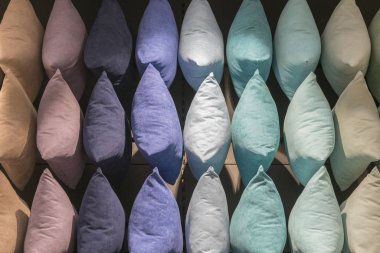 Çok renkli yastıkların arka planı. Yastıklardan yapılmış yaratıcı bir arka plan. Mor, mavi, bej, gri yastıklar.