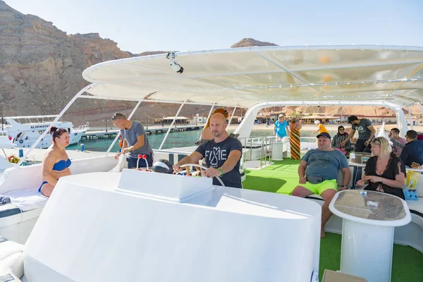 Sharm El Sheikh, Egypt - November 26, 2019: Bald captain driving pleasure boat with tourists. Happy tourists on pleasure yacht. Sea vacation concept.