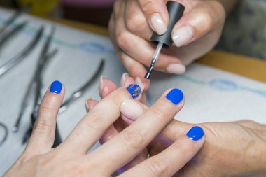 Beautiful manicure process. Nail polish applying, polish in blue color. Close up.