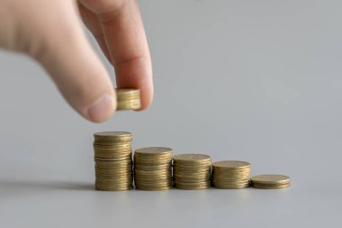 Saving money concept preset by male hand putting money coin stack on gray background. growing business.