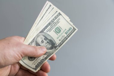 Hand holding money us dollar on grey background. Hand holding 100 Dollar bills. 