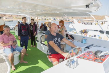 Sharm El Sheikh, Egypt - November 26, 2019: Bald captain driving pleasure boat with tourists. Happy tourists on pleasure yacht. Sea vacation concept.