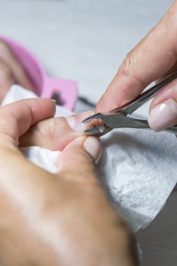 Cuticle Cutting. Woman hands receiving manicure and nail care procedure. Close up concept. 