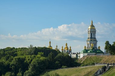Christian church on the green hills. The bell tower with golden domes. Christianity concept. Old church. 