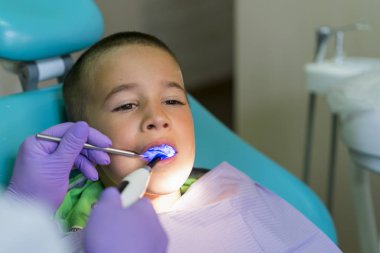 Dentists with patient during dental intervention to boy. Dentist Concept.  