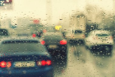 Yağmurlu bir günde trafik yoğundur. Yağmurlu bir günde trafik vardı. Araba penceresinden yol manzaralı ve yağmur damlaları vardı. Bulanık resim.