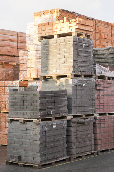 Several pallets with concrete bricks stacked on top of each other in depot. Industrial production of bricks.