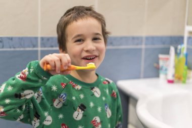 Genç bir çocuğun diş fırçasıyla dişlerini fırçaladığı mutlu bir yüzle dişlerini fırçaladığı mutlu bir çocuğun banyo odasında küçük dişlerini fırçaladığı diş konsepti..