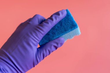 Pembe arka planda havluyla eldivenli bir el. Plastik eldivenler ve pembe arka planı temizlemek için bir bez. Lastik eldiven ve sünger seti. Koruyucu eldiven ve el bezi bileşimi.