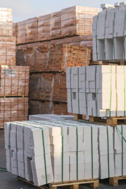 Depoda üst üste yığılmış beton tuğlalı birkaç palet. Endüstriyel tuğla üretimi. dikey resim.