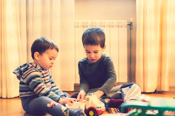 Zwei kleine Brüder spielen im Spielzimmer mit einem Krankenwagen. gemildert — Stockfoto