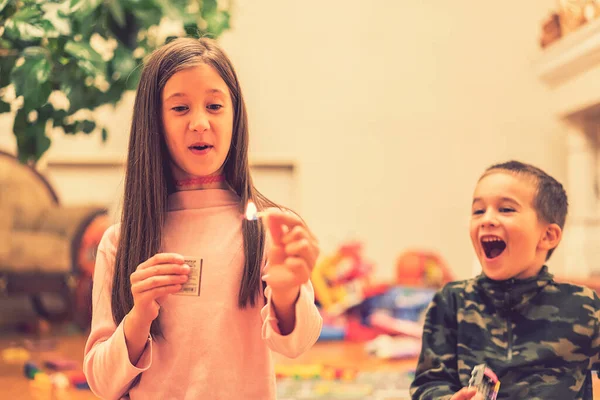 Small children playing with fire at home. A child plays with matches in the foreground a burning match, a child and matches, a fire, dangerous. toned — Stock Photo, Image