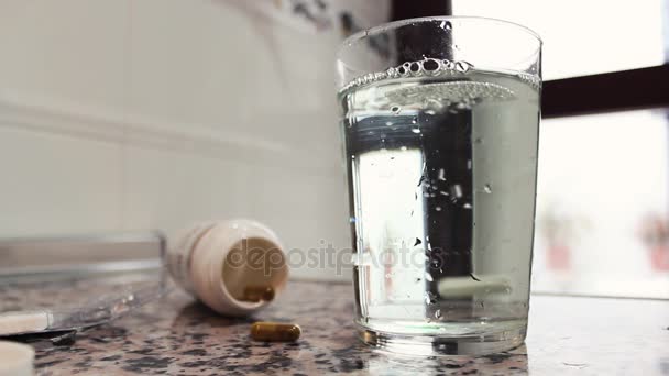 Hand wirft eine Tablette in Glas mit Wasser und rühren — Stockvideo