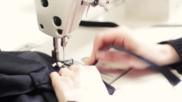 Женщина, работающая над швейным проектом, когда режет ткань и пришивает её к машине. швейная машинка закрывает руку портнихи поддерживая ткань во время шитья на машине — стоковое видео