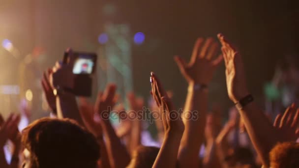 Flicka i publiken skjuter video på smartphone.girl stående i mitten av konserten publiken och hålla mobiltelefonen i händerna. — Stockvideo