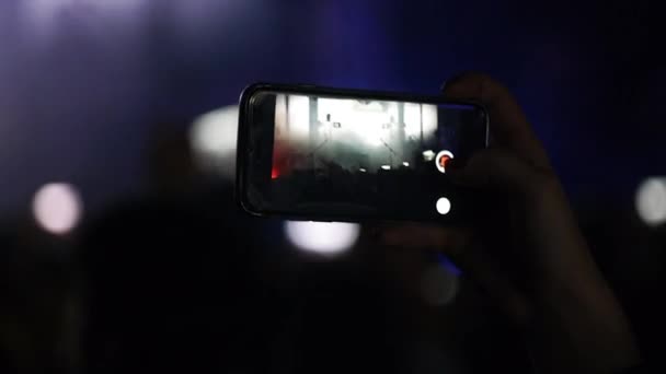Chica en la multitud dispara video en smartphone.girl de pie en medio de la multitud concierto y la celebración de teléfono móvil en sus manos . — Vídeos de Stock