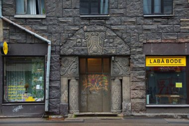 Riga 'nın merkez caddelerinden birinde ulusal romantizm tarzında bir konut kapısı olan ön cephenin bir parçası.