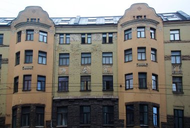 Riga 'nın merkez caddelerinden birinde ulusal romantizm tarzında bir konut kapısı olan ön cephenin bir parçası.