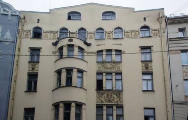 Riga 'nın merkez caddelerinden birinde ulusal romantizm tarzında bir konut kapısı olan ön cephenin bir parçası.