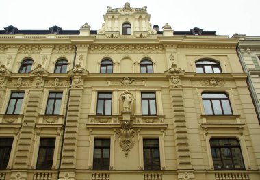 Riga 'nın merkez caddelerinden birinde ulusal romantizm tarzında bir konut kapısı olan ön cephenin bir parçası.