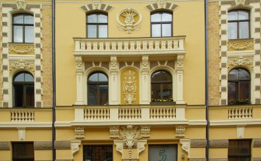 Riga 'nın merkez caddelerinden birinde ulusal romantizm tarzında bir konut kapısı olan ön cephenin bir parçası.