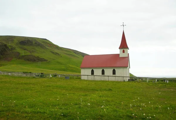 Summer walk in the vicinity of the town of Vic, red flowers and a church by the road to the black beach of Reinisfjara