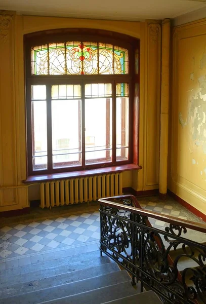 A fragment of the architectural design of the interior in the style of a modern apartment building in the city center, a window and a stained-glass window of the main staircase