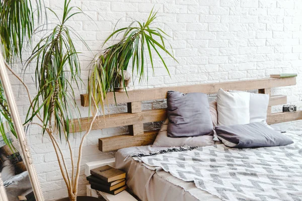 Interior de ladrillo blanco claro con espejo en la esquina, cama y almohadas — Foto de Stock