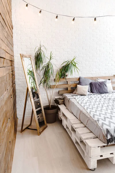 Studio creativo interno bianco con letto pallet, specchio e lampade — Foto Stock