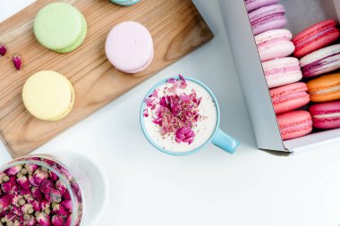 Lezzetli Fransız macarons ve bir fincan kapuçino gül yaprakları ile