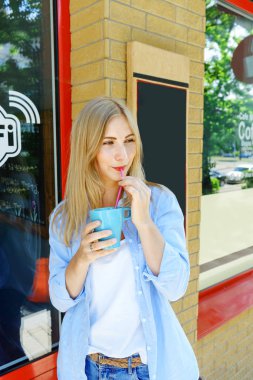 Kahve içme çekici kızı. Kot pantolon giymek ve sarı saçlı güzel