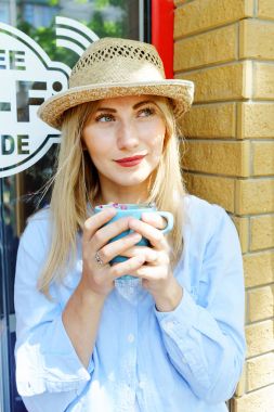 Bir fincan kapuçino elinde tutan güzel genç sarışın kız. Düşünceli düşünme