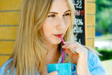 Sarışın kız portre güzel yüzün. Bir fincan kapuçino ve rinking tutarak. Düşünceli görünüm