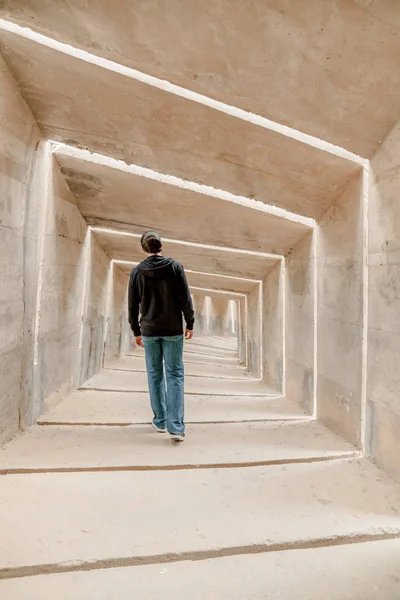 Vista trasera del hombre caminando solo en el pasillo del túnel. Pasarela urbana subterránea solitaria. Movimiento de peligro adulto único — Foto de Stock