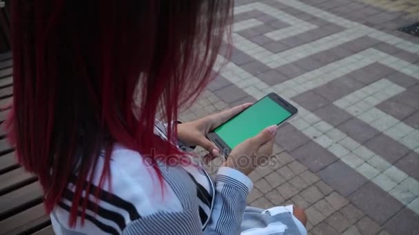 女の子公園で座っているドレスし、スマート フォン クロマキー スクリーンを使用 — ストック動画