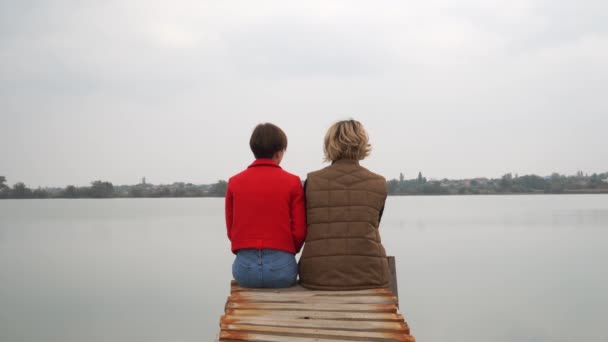 Young womans sits on old wooden pier ans speak — Stock Video